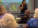 Woman presenter speaking to seated audience with bird images projected on screen