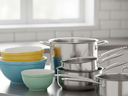 Stacked colorful mixing bowls and stainless steel pots on a kitchen countertop