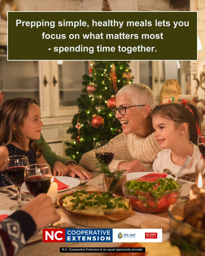 An older woman and two young girls smile and laugh together at a holiday dinner table. A lit Christmas tree stands in the background. Text at the top reads: "Prepping simple, healthy meals lets you focus on what matters most - spending time together." The N.C. Cooperative Extension logo is at the bottom.