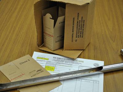 Table with soil testing boxes, a soil probe, and a form, showing the supplies needed for soil testing provided by the NCDA&CS Agronomic Division.