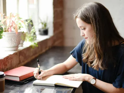 Woman Sitting down writing in notebook