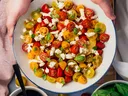 picture of bowl of tomato salad with orannge and red cherry tomatoes and feta cheese and other vegetables