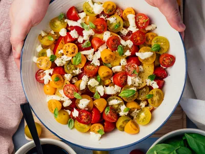 picture of bowl of tomato salad with orannge and red cherry tomatoes and feta cheese and other vegetables