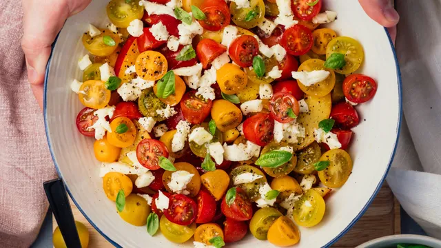 picture of bowl of tomato salad with orannge and red cherry tomatoes and feta cheese and other vegetables