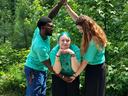 Three people in teal shirts forming an arch over a person standing with hands under chin