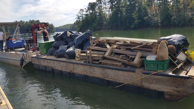 A barge filled with trash including wood, foam, and full bags of trash from the Lake James Clean Up.
