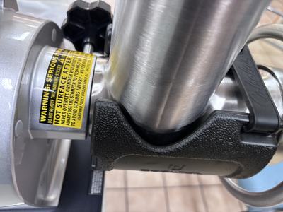 Stainless steel mixer tube in black clamp beside yellow label reading "HOT SURFACE"
