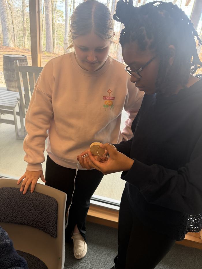 Youth showing other youth how to make colonial toy