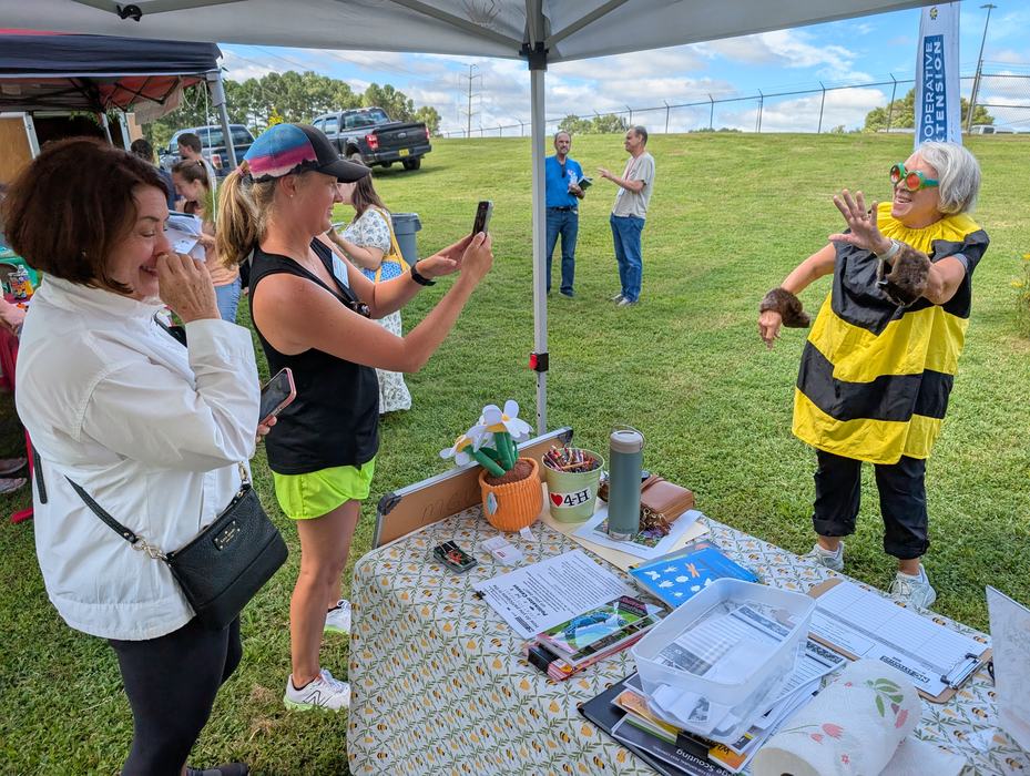 A woman in a bee costume has her picture taken by extension master gardener volunteers for social media.