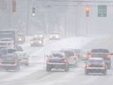 Cars at a traffic intersection during a snow storm.