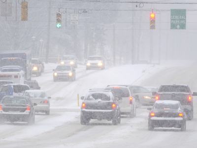 Cars at a traffic intersection during a snow storm.