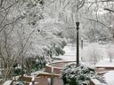 Snow-covered brick stairway with lamp posts and trees in a winter park