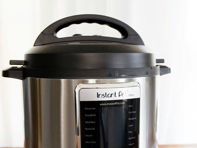 Instant Pot pressure cooker on marble countertop showing front control panel labeled "Instant Pot"