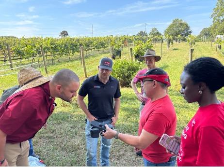 The PSI Team inspects a device while working in the vineyard.