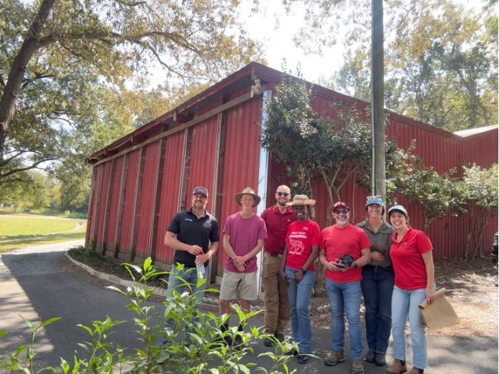 The PSI team pose with a building at the vineyard.