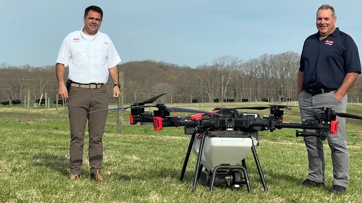 NC State Extension experts Miguel Castillo and Seth Nagy stand on either side of an agricultural drone