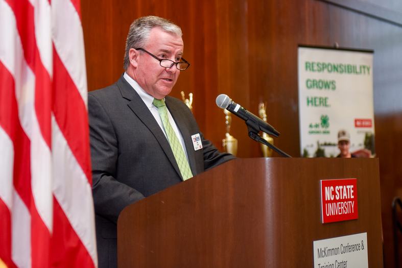NC State Extension state 4-H program leader Mike Yoder speaking at a podium during a conference.