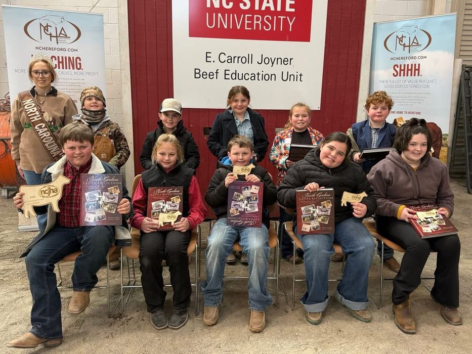 Group of children holding awards under "NC STATE UNIVERSITY" sign, E. Carroll Joyner Beef Education Unit