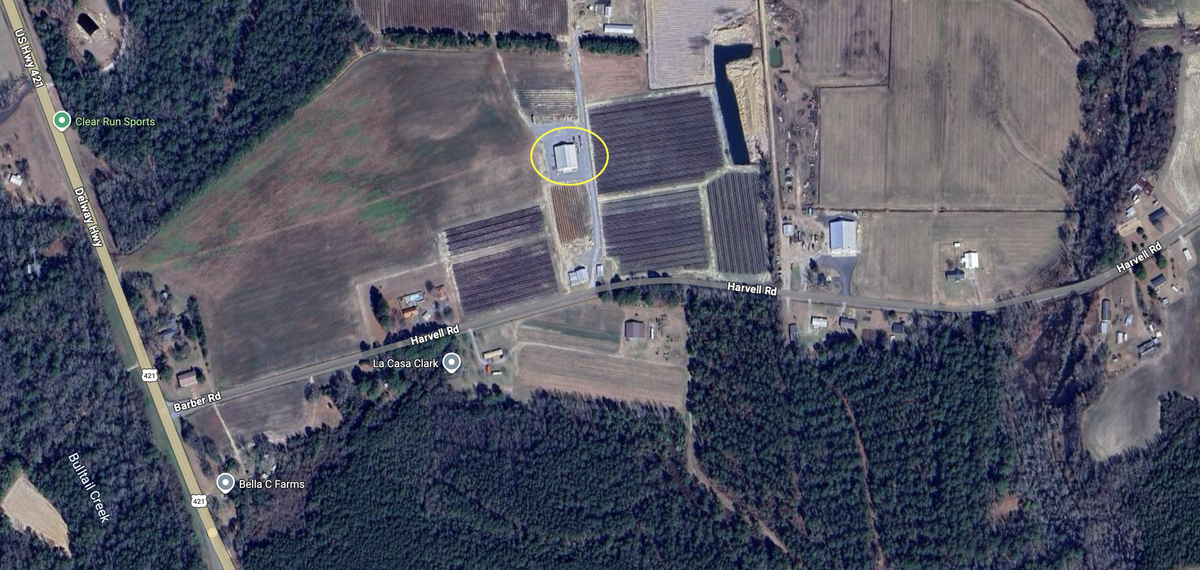 Aerial view of farmland with rectangular crop fields and a circled building near Harvell Rd