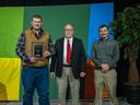 Three men standing; left man holding plaque reading "2nd Place Dryland"