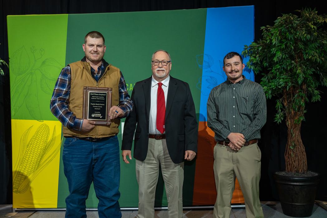 Three men standing; left man holding plaque reading "2nd Place Dryland"