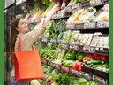 Young adult female reaching for an item in the produce section of the grocery store