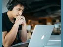 A man sitting at a desk working on a laptop.