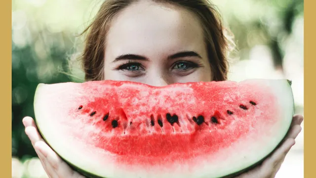 A woman holding a watermelon slice in front of their face with eyes visible above it.