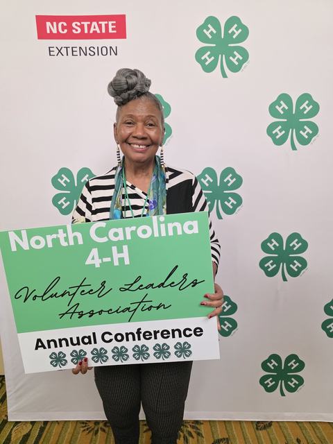 woman holding a 4-H sign