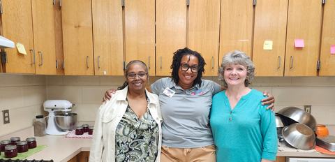 Thre women stand together smiling