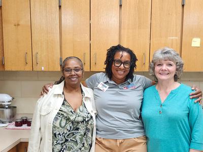 Thre women stand together smiling