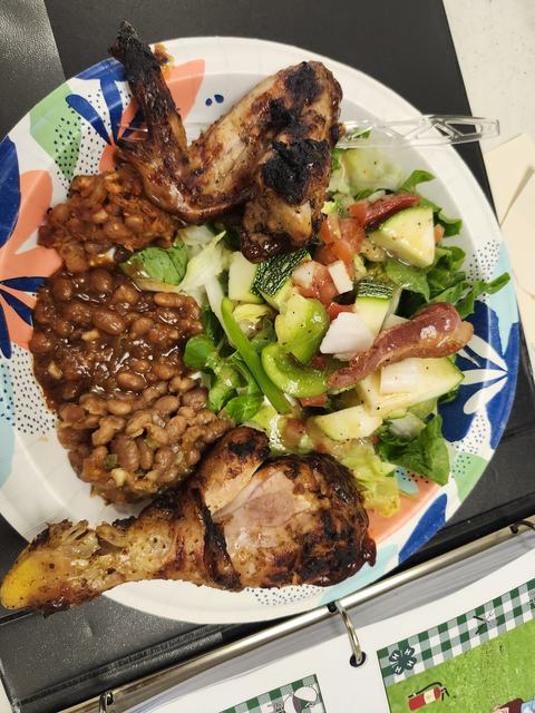 A plate of food containing grilled chicken, fresh summer salad, and baked beans.