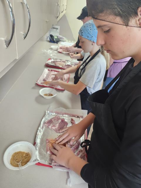 Youth layout their pork chops on trays as they begin to add their seasoning blends.