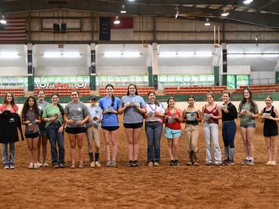 Several of the 2026 Achievement Award winners are posing with their prizes in the main arena of the Hunt Horse Complex.