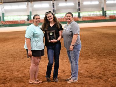 Ruth Vorder Bruegge is holding her plaque for receiving the 2026 Candace Norman Adult Volunteer Leader award. On each side of her are Jessica McVey and Morgan Maness, members of the North Central District 4-H Horse Advisory Council who sponsored the award