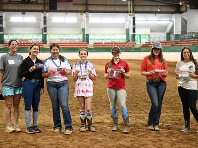A group of youth with their 2025 recreational riding rewards awards in the main arena of the Hunt Horse Complex.