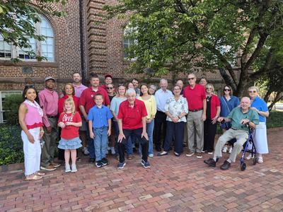 Members of the NCTTFC ALDP alumni and their families pose for a picture in front of Holliday Hall, the first building of NC State.