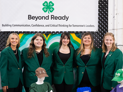 State 4-H Officers, wearing their official green jacket attire, posed together for a group photo at the NC 4-H booth of the 2025 N.C. State Fair.
