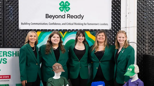 State 4-H Officers, wearing their official green jacket attire, posed together for a group photo at the NC 4-H booth of the 2025 N.C. State Fair.