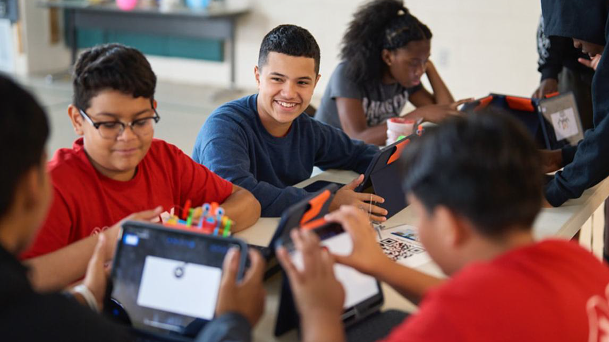 Several 4-H youth work together using iPads during a STEM activity focused on app development and digital content creation.