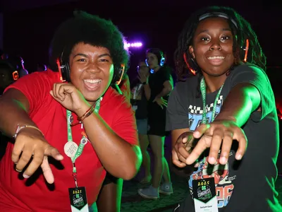 Two 4-H members wearing LED headphones point toward the camera while participating the silent disco at 4-H Congress.