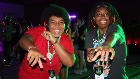 Two 4-H members wearing LED headphones point toward the camera while participating the silent disco at 4-H Congress.