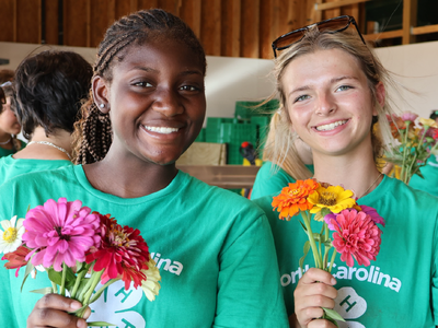 Two 4-H'ers holding flowers while participating in a service project.