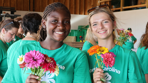 Two 4-H'ers holding flowers while participating in a service project.
