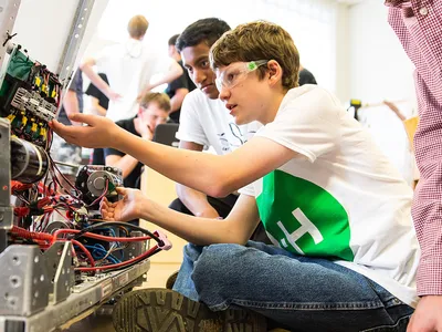 4-H members collaborate in a workshop, assembling and troubleshooting a robot.