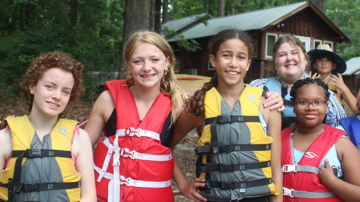 Several youth at 4-H camp wearing life jackets.
