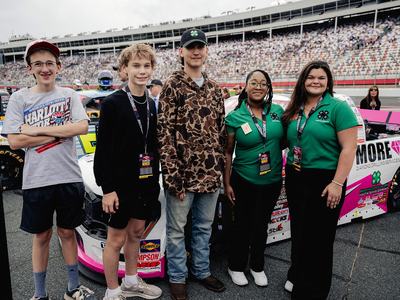 Youth from the NC State Extension 4-H program in Harnett and Moore counties stand in front of a race truck at Charlotte Motor Speedway