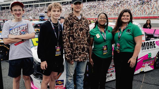 Youth from the NC State Extension 4-H program in Harnett and Moore counties stand in front of a race truck at Charlotte Motor Speedway