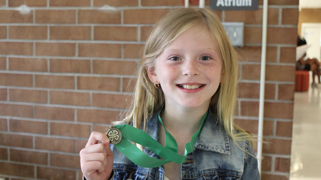 4-H'er holding a gold medal that she was awarded for her presentation at state finals.