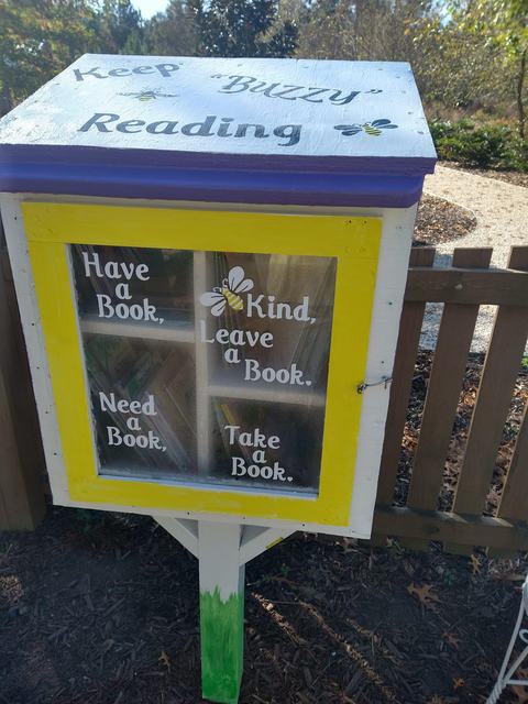 Little book library in the children's garden decorated with painted bees.